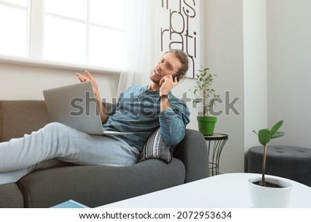 Handsome young man talking by mobile phone while working at home