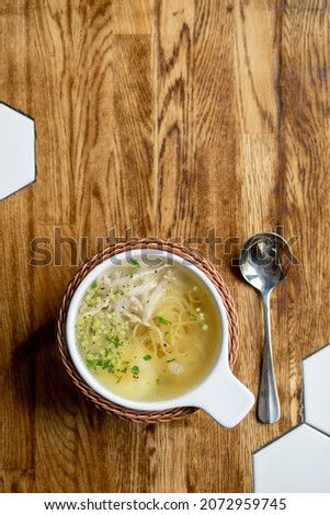 chicken soup, chicken broth. against the background of a wooden steel in a cafe