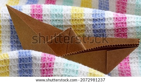 origami paper boat on colorful fabric background