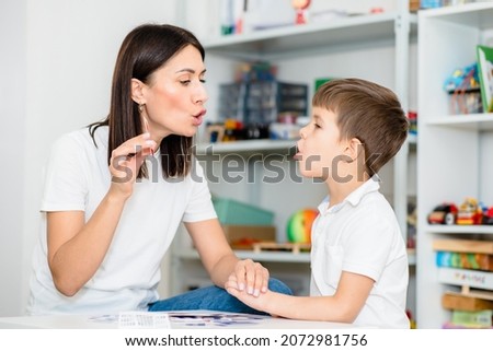 A cute child with a speech therapist is taught to pronounce the letters, words and sounds correctly. Royalty-Free Stock Photo #2072981756