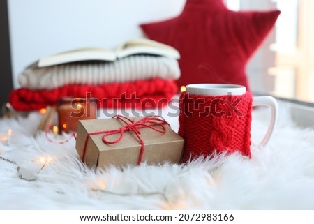 Red knitted cup with a drink on a Christmas background. New Year's home comfort.