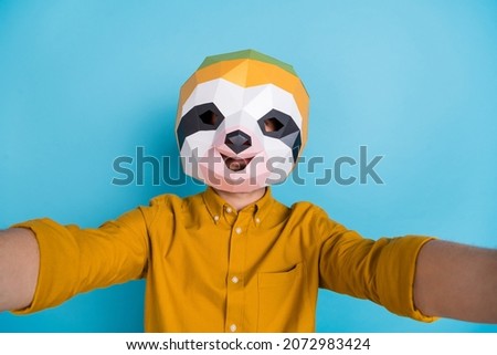 Photo of blogger sloth man hold camera take selfie wear polygonal mask yellow shirt isolated blue color background