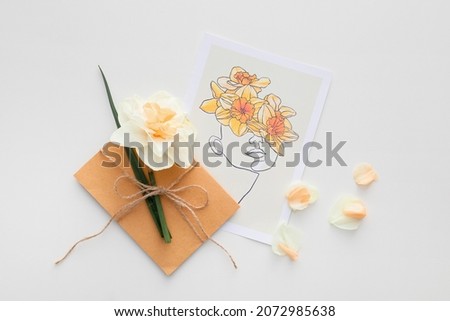 Beautiful greeting card, narcissus flower and envelope on light background