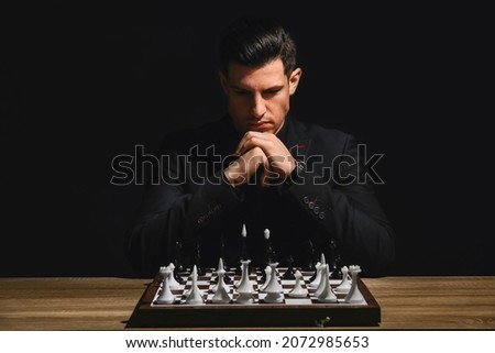 Man playing chess at table on dark background