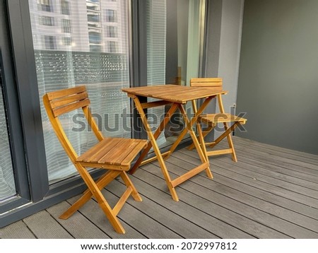 Wooden folding chairs and a table are located on the outdoor balcony. Home terrace. Patio furniture. Royalty-Free Stock Photo #2072997812