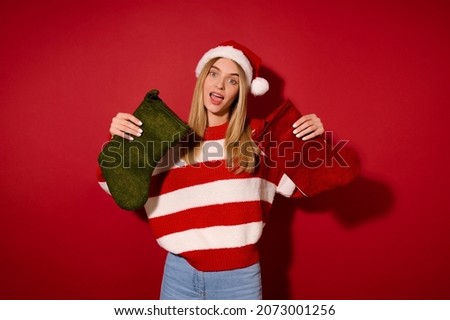 A girl in santa hat holding christmas stockings