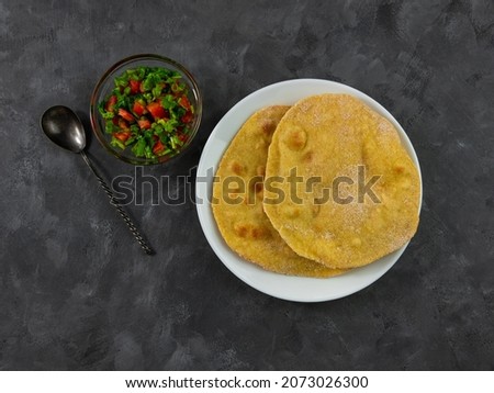 Homemade corn flatbread with cilantro greens tomato salsa. Handmade mexican tortillas vegetable salad. Traditional Indian Punjabi Makki ki roti bread plate top view Wheat flour dough authentic cuisine