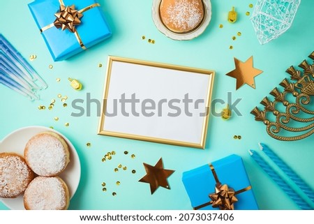 Picture frame mock up for Jewish holiday Hanukkah  with traditional donuts, menorah and gift box on blue background