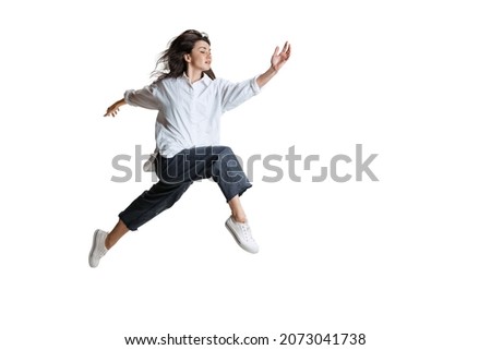 Passing. Young woman in casual wear moving dynamically isolated on white background. Flexible female ballet, contemporary dancer weightless moves. Art, motion, action, flexibility, inspiration concept Royalty-Free Stock Photo #2073041738