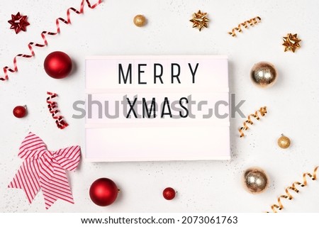 Christmas frame with balls, red, golden decorations on white background and lightbox with the text merry christmas. New year planning concept. Flat lay, top view, copy space.