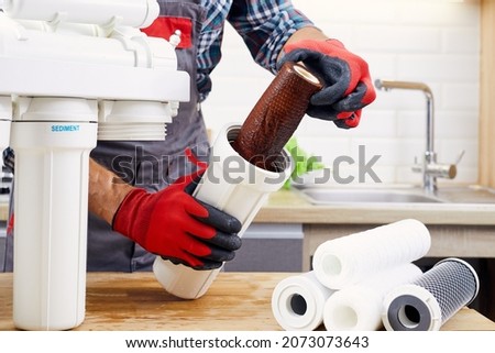 Plumber installs or change water filter. Replacement aqua filter. Repairman installing water filter cartridges in a kitchen. Installation of reverse osmosis water purification system.
 Royalty-Free Stock Photo #2073073643