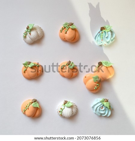 A group of colored meringue pumpkins decorated with sprinkles in a dramatic form on a white background