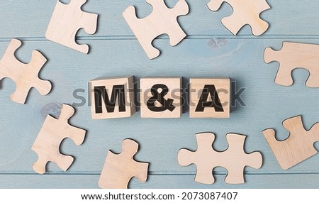 Blank puzzles and wooden cubes with the text M AND A lie on a light blue background.