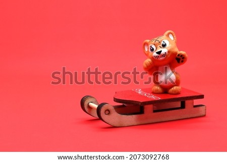 Year of the tiger, Christmas decorations tiger on a sleigh, on a red background, a place to copy text