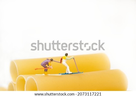 miniature figures people ski on cannelloni pasta. White background . copy space
