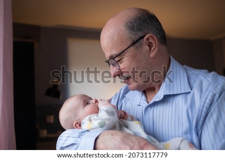Grandfather holding a beautiful newborn baby girl Royalty-Free Stock Photo #2073117779