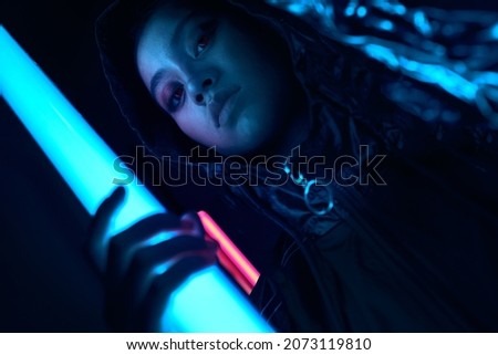 Portrait of young asian teenage girl in red neon light. Cyber, futuristic portrait concept, looking forward