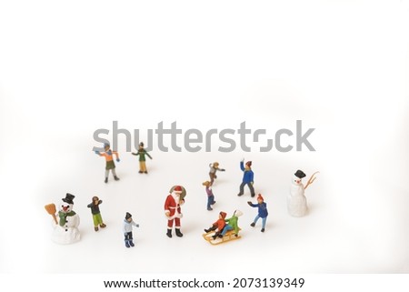 children playing in the snow, santa claus and snowman are also there. top view, miniature figures scene on white background. copy space