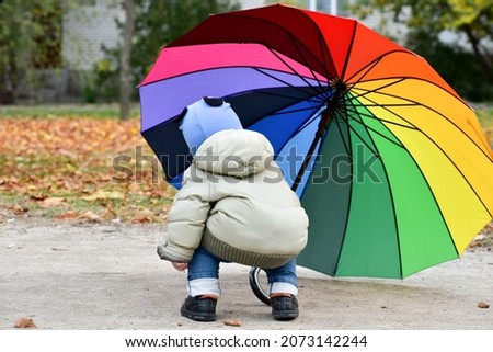 One year child holds rainbow colors umbrella  , autumn vibe , childhood