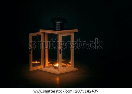 Old lantern with a burning candle on a dark background.