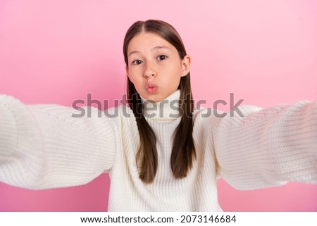 Photo of shiny adorable preteen girl dressed white pullover recording self video sending kiss isolated pink color background