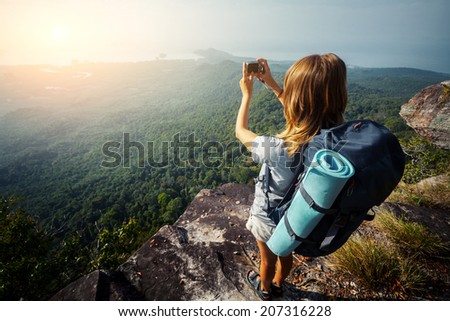 Female hiker taking picture of the valley from top of the hill