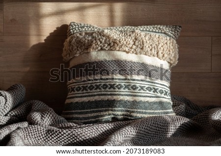 Warm and cozy woven decorative handmade cushion made of wool in modern room interior  Royalty-Free Stock Photo #2073189083