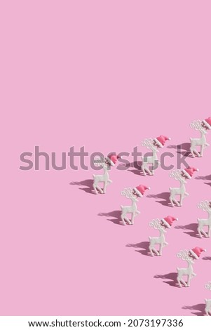 Pattern with a glamorous reindeers in a Santa hat on a pink background with copy space