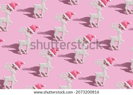 Pattern with a glamorous reindeers in a Santa hat on a pink background