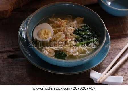 A bowl of Mie Godog, is a soup noodle dish that is added with vegetables such as caisin and protein such as eggs, meatballs, etc.
