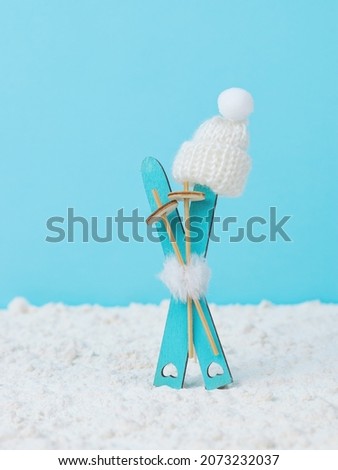 White knitted hat wearing wooden skis on snow on a blue background. Winter sports.