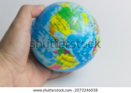 blurred image of a hand holding 3D earth globe with white background