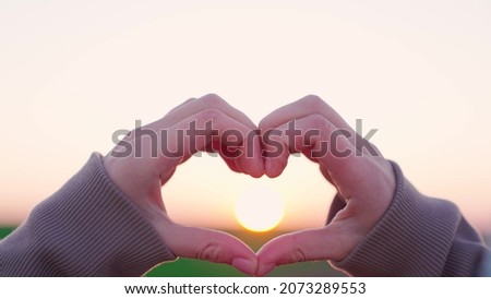 showing with hands a heart symbol at sunset, happily traveling freely in life, loving the rays of sunlight, a romantic man making a valentine sign stick figure on background of sky, gesture of health