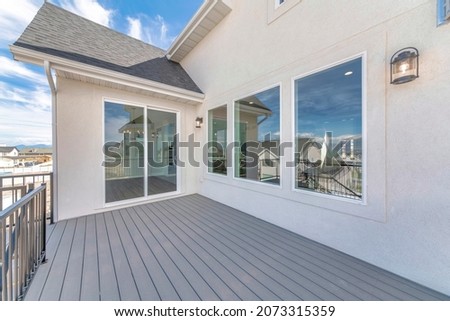 Deck of a house with reflective sliding glass door and picture windows