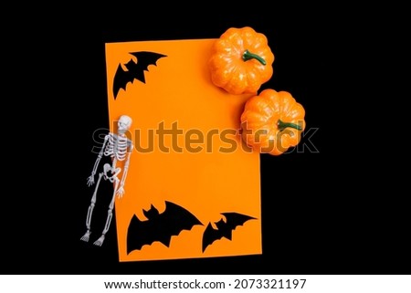The concept of a happy Halloween holiday. Halloween decorations, bats, pumpkins, skeleton on an orange background. A mock-up of a Halloween greeting card with a place to copy.