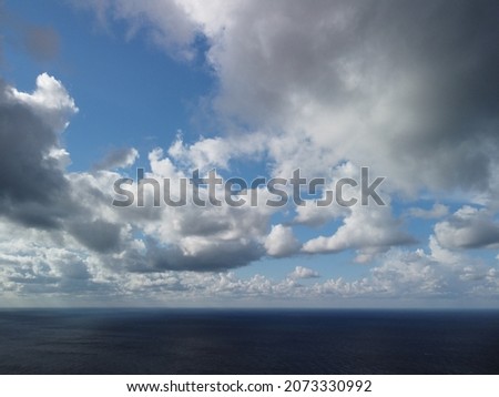 Abstract airy sky with moving plump clouds over the sea ocean. Small waves on clear water surface bokeh lights from sunrise. Holiday, vacation and recreational concept