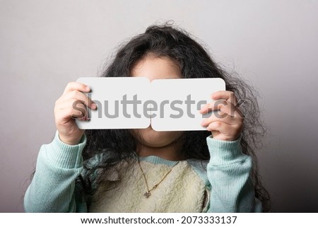 Little girl portrait holding two flash card in front of face, preschooler educational material learning objects. flash cards selection path included.