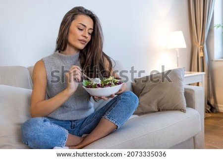 Beautiful healthy woman eating salad, Dieting Concept. Healthy Lifestyle.  Woman eating fresh salad in a bowl at home with a happy face standing and smiling with a confident smile  Royalty-Free Stock Photo #2073335036