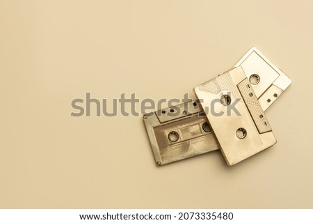 Gold fancy retro old audio cassettes tape on beige color background. Retro mixtape, 1980s pop songs tapes and stereo music cassettes