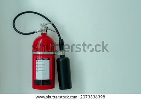 black red fire extinguisher stuck on a white concrete wall in a house