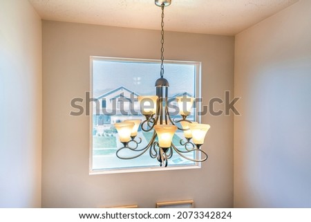 Hanging uplight chandelier against the square picture window
