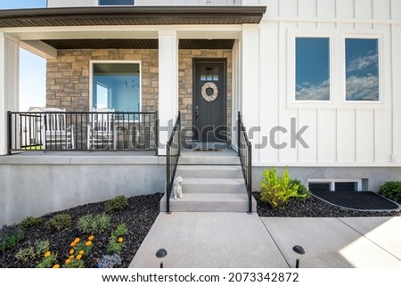 Facade of a house with stone veneer and white board and batten sidings Royalty-Free Stock Photo #2073342872