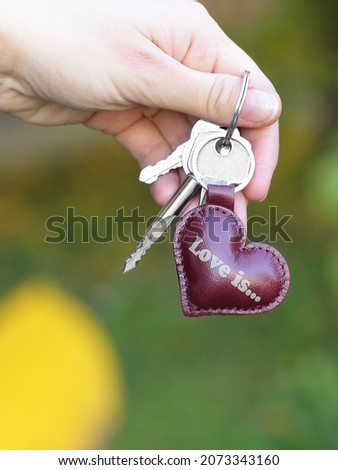brown leather key trinket heart shape closeup photo in human hands 