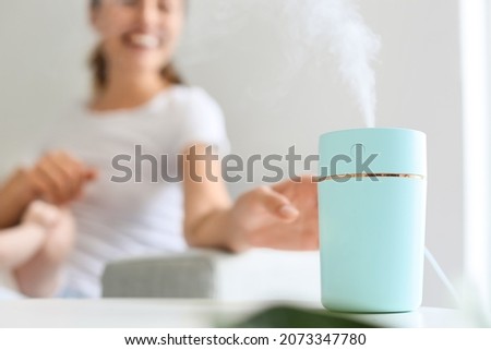 Young woman with modern humidifier at home Royalty-Free Stock Photo #2073347780