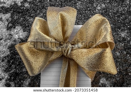 A gift box decorated with a bow. Golden-copper gamma. Icy surface. Concept: Christmas, New year, gifts and greetings, holiday card, birthday, wedding gift, date.