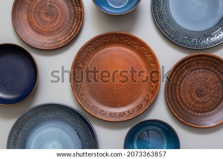 set of blue and brown bowls, plates on gray background, top view, Set of clay utensils on white wooden tabl
