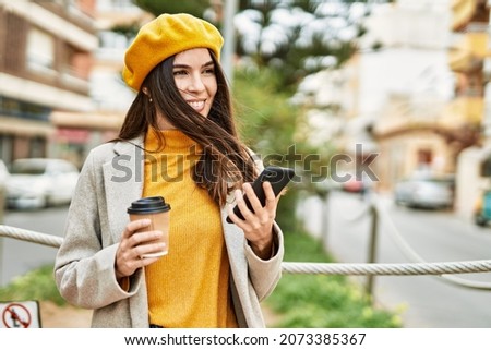 Young hispanic girl using smartphone drinking coffee at the city.