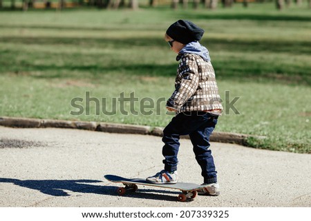 little funny boy with skateboard on the street