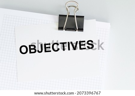 White notebook with card with text OBJECTIVES on clip, business concept