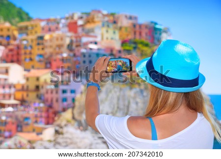 Back side of young woman taking picture of beautiful colorful old Italian buildings, happy travel to Europe, summer vacation concept